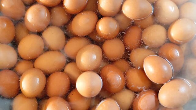 Chicken eggs are being boiled in hot, boiling water. abundant chicken eggs. Top view.