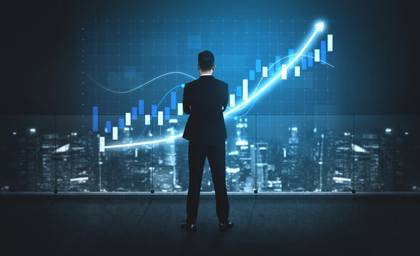 A business professional stands in a modern office, gazing at a digital financial growth graph, symbolizing market trends and investment success. Impute