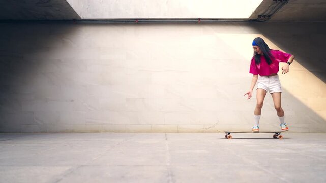 Young Asian woman practicing longboard skateboard on urban public park during late afternoon enjoy active lifestyle outdoor recreation balance fitness freedom healthy leisure and modern city mobility
