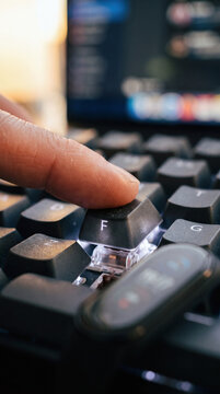 Macro extreme close up of finger pressing F key on illuminated mechanical keyboard