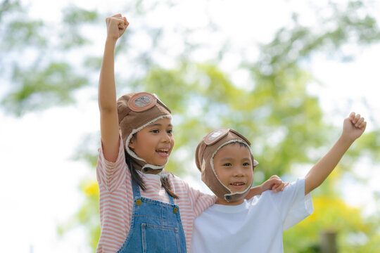 Happy Children Wearing Aviator Hats Raising Their Fists in Victory, Celebrating Friendship, Teamwork, Imagination, Adventure, and Joyful Childhood Outdoors.