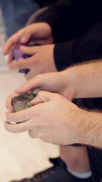 Manos de dos jugadores utilizando controles de videojuegos. Primer plano de jugadores compitiendo en videojuegos. Gaming multijugador con controles en primer plano. Dos hombres jugando videojuegos.