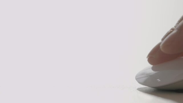 A close-up of a white Apple Magic Mouse on a white desk surface with soft minimal lighting.