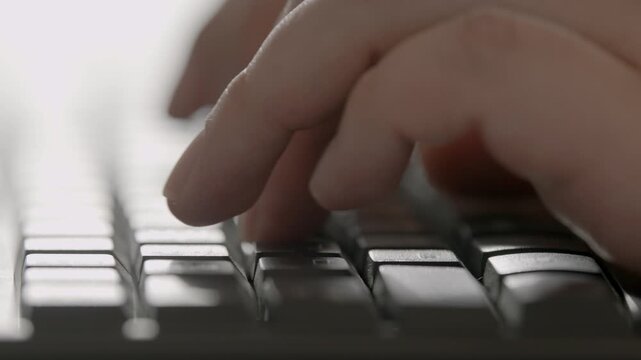 A close-up of fingers resting on or typing a white keyboard with soft lighting in a clean minimal workspace.