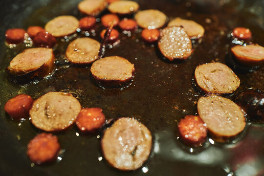 Sausage slices sizzling in a hot frying pan