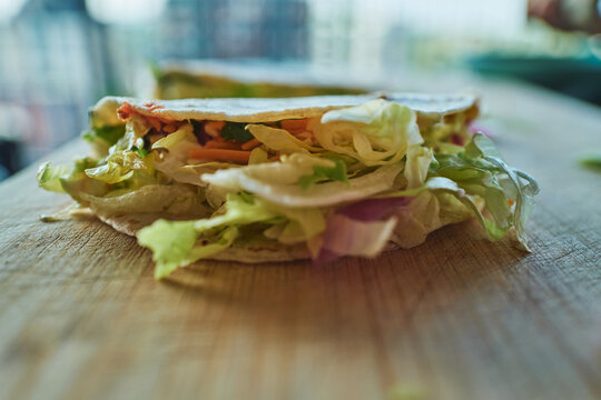 Filled tortilla wrap with fresh vegetables on a cutting board