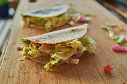 Two homemade tacos filled with salad on a wooden board