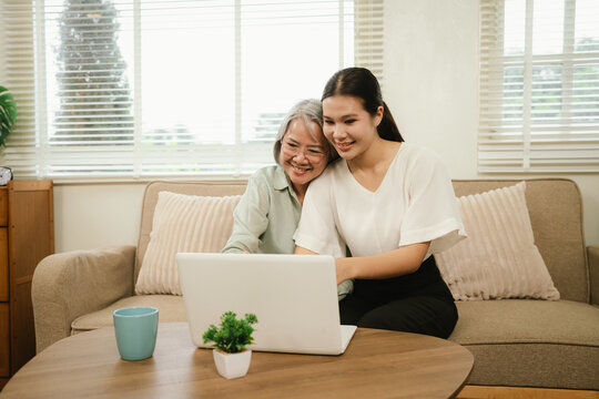 Senior woman and young caregiver using a laptop together at home, promoting digital inclusion, family support, and elderly technology learning.