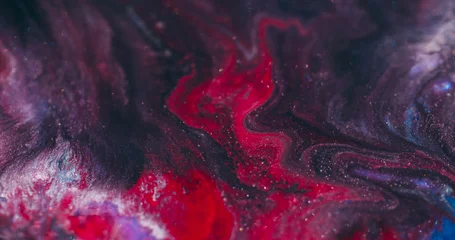 Shimmering acrylic. Art fluid blur. Red paint wavy lava stream swirling in black sparkling liquid on abstract color flare background. © golubovy