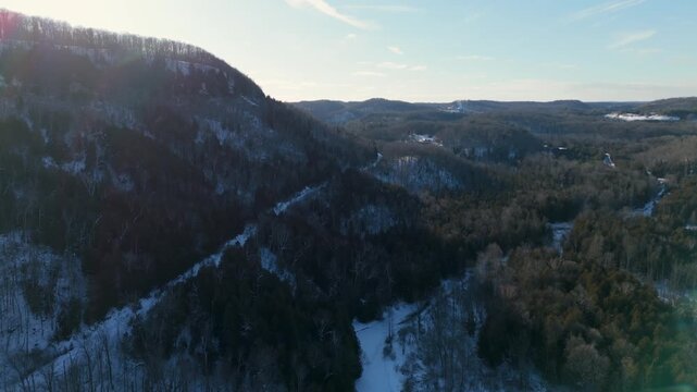 Majestic drone video glides over Devil's Pulpit in Forks of the Credit, Caledon, with sunlit winter forests, dramatic snowy slopes, and sweeping blue sky in crisp daylight aerial footage.