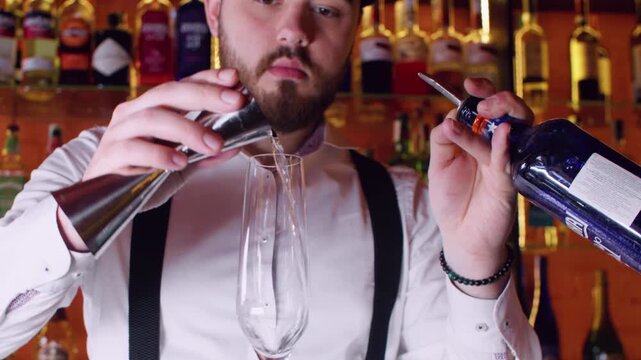Drink service. Cocktail making. Professional male pouring alcohol liquid using shot measure jigger in transparent glass on bar counter.