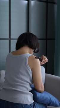 Asian mature woman using gua sha massage her back