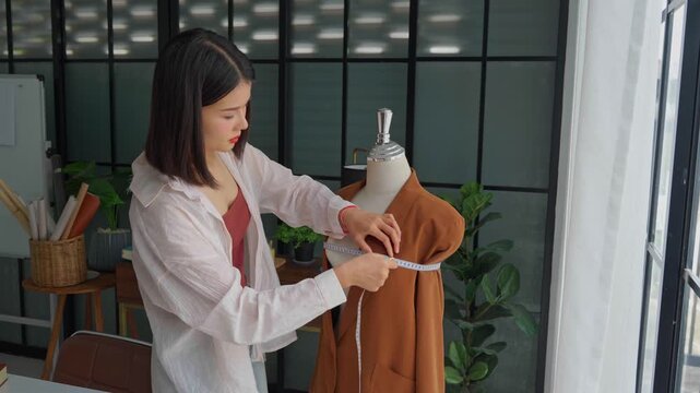 Asian woman designer using measuring tape measure cloth on clothing try-on stock