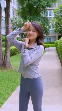 Asian sport woman standing and wiping sweat from her brow in park