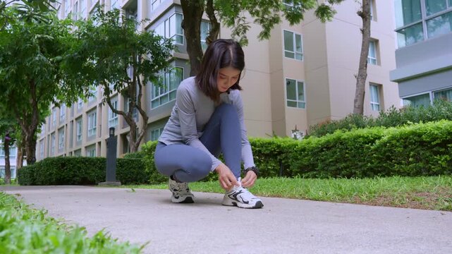 Asian sport woman tying sneaker lance in park