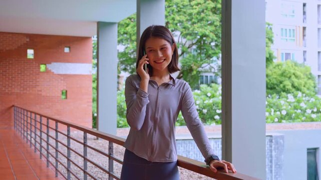 Asian woman in sport wear talking to smartphone