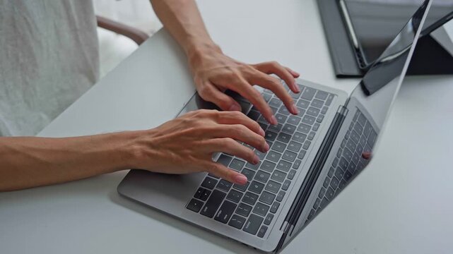 Asian businessman typing on laptop with tablet on table