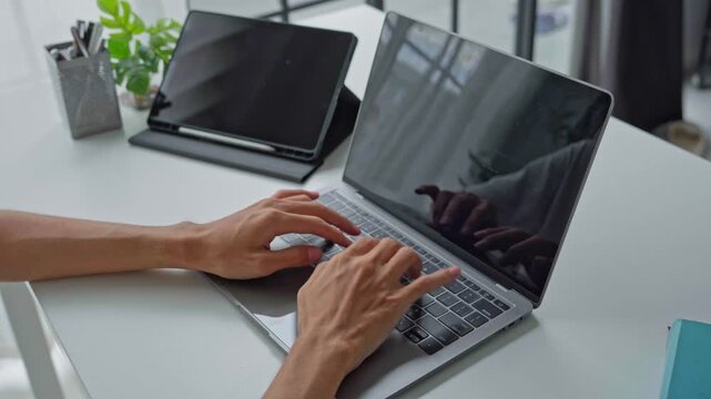Asian businessman typing on laptop with tablet on table