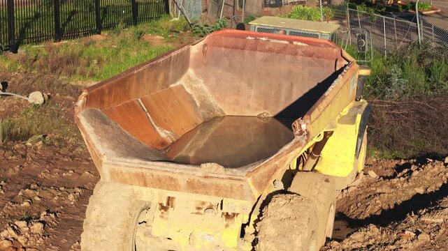 Articulated dump truck reversing on a muddy construction site