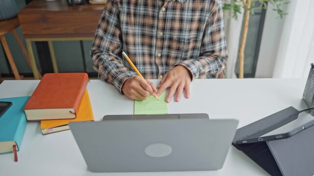 Asian businessman taking note during vdo conferrance on laptop