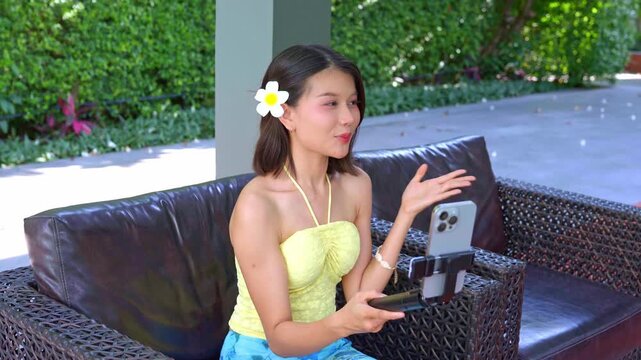 Asian woman in swimsuit sit on sofa using smartphone live streaming on social platform