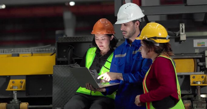 Engineer and workers discussing over laptop on platform at steel factory production line