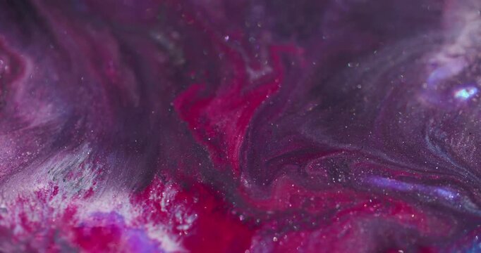 Glitter mix. Art fluid. Red pink paint wavy stream swirling in black sparkling liquid on defocused abstract color flare background.