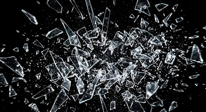Sharp shards of broken glass exploding and flying through the air, isolated on a black background.