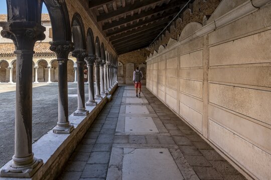 Young man in the cloister with graves, church Chiesa di San Michele in Isola, cemetery island San Michele, Venice, Italy
