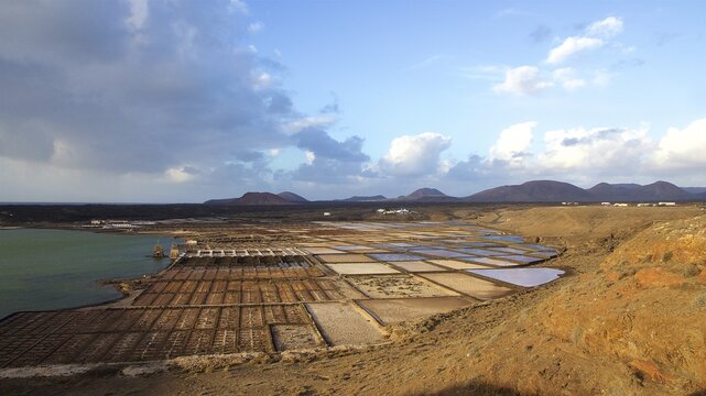 Salt pans, salt production, salt pans by the sea, lava mountains, blue sky, grey-white clouds, south, Lanzarote, Canary Islands, Spain