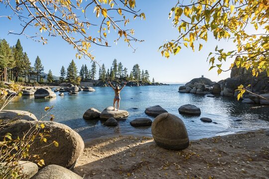 Young woman in bikini standing on a round stone in the water, bay at lake Lake Tahoe, Sand Harbor State Park, shore, California, USA