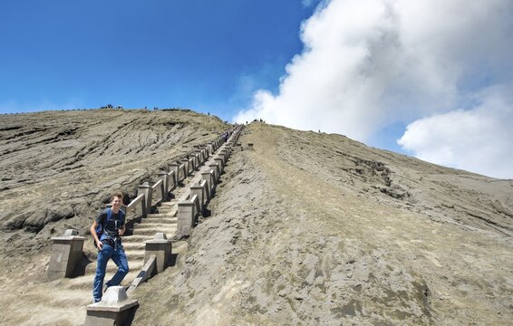 Young man on the stairs to the crater rim of the smoking volcano Gunung Bromo, National Park Bromo-Tengger-Semeru, Java, Indonesia