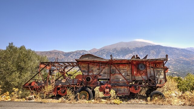 Antique, rusty combine harvester in front of a mountain backdrop under a bright sky, Vehicle wreck, Crete, Greek Islands, Greece