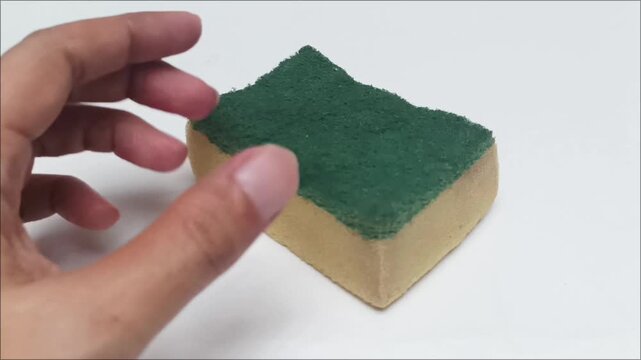 Hand holding kitchen dishwashing sponge on white background