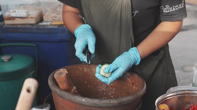 Chopping fresh cucumber for som tam salad at Thai food stall