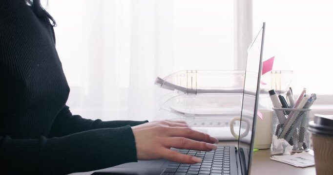 Female manager. Internet freelance. Unrecognizable entrepreneur working at desk typing on laptop at workplace for professional occupation.