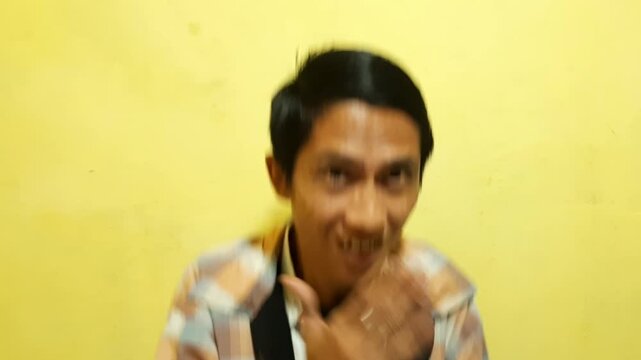 Portrait of a young Asian man wearing a casual patterned shirt, performing various expressive gestures and looking at the camera against a yellow background.