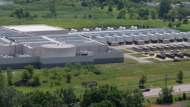 Aerial zoom in view of a modern data center facility featuring solar panels and cooling units