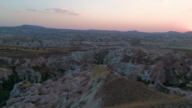 Goreme, Nevsehir, Turkey. Red Valley, eroded tuff rock formations glowing in warm sunset light, panoramic aerial view over the vast Cappadocian landscape. Aerial View, MasterShots, Spiral forward