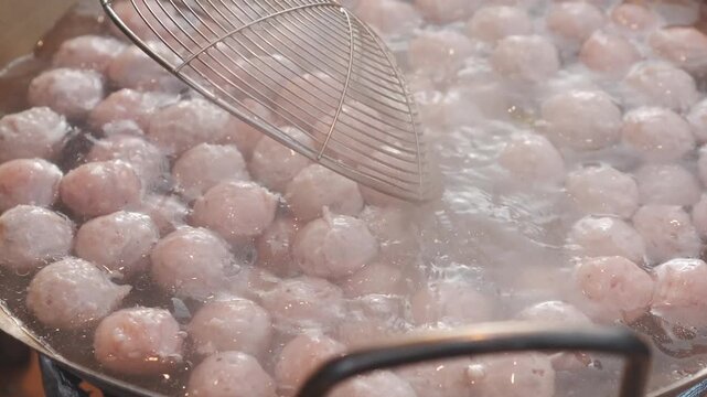 Chicken meatballs cooking on hot grill at Thai night market