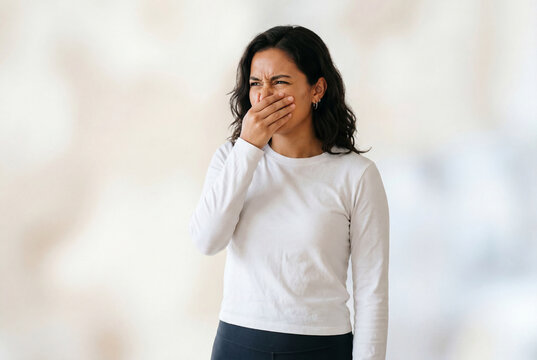 Young woman covering nose with hand due to bad smell or odor
