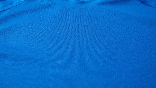A blue athletic t-shirt lies flat on a green surface