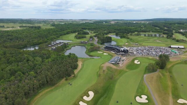 Aerial footage captures TPC Toronto Osprey Valley Golf Course&rsquo;s lush fairways, pristine sand bunkers, water hazards, and surrounding green forest under bright daylight in a sweeping bird's eye view.