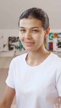 Beautiful young woman looking directly at the camera with a neutral expression, slowly breaking into a warm and gentle smile, showcasing a genuine and positive emotional change in her studio