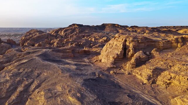 Aerial view of dry yardang landforms with rugged sandstone formations under sunset light in Dahaidao, Xinjiang, China