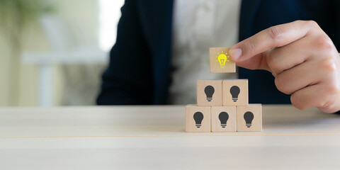 Business Insight and Innovative Thinking. Glowing light bulb block on a pyramid of idea icons, Innovation, creative leadership, strategic growth, breakthrough thinking and business success. © Parradee