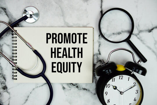 Promote Health Equity text written on notepad with stethoscope and magnifying glass on marble background