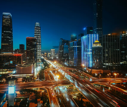 Elevated city view of Beijing CBD skyline featuring China Zun tower and Guomao (China World Trade Center, China World, China World Towers, CWTC) overpass with traffic light trails at twilight