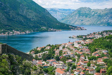 Fototapeta premium Scenic view of historic Kotor city with colorful buildings surrounded by mountains and calm bay with lush greenery in Montenegro.