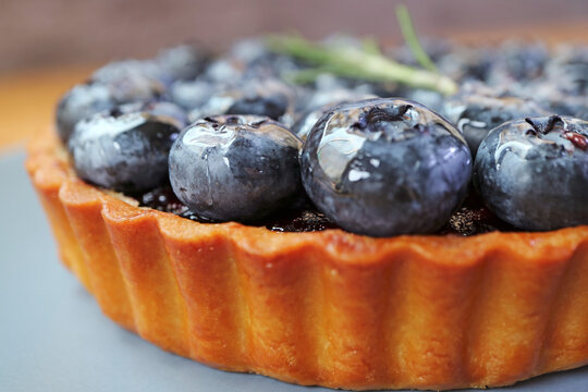 Macro front view of a crispy golden crust blueberry tart packed with fresh ripe berries